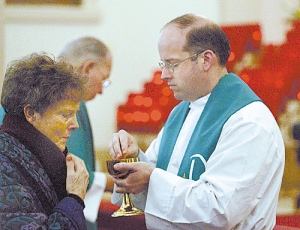 The Rev. Nikola Derpich, ordained in 2006 as a Catholic priest at the Vatican, administers communion to Gerrie Ridgeway during Mass Tuesday at Our Lady Help of Christians Church in Watsonville